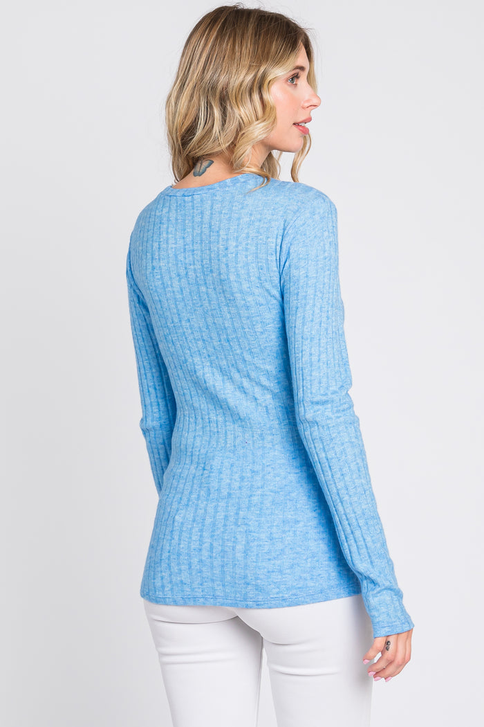 woman wearing a light blue ribbed long sleeve top with a fitted silhouette and slightly longer back hem