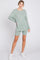 woman wearing a light green oversized sweater and matching shorts with white sneakers