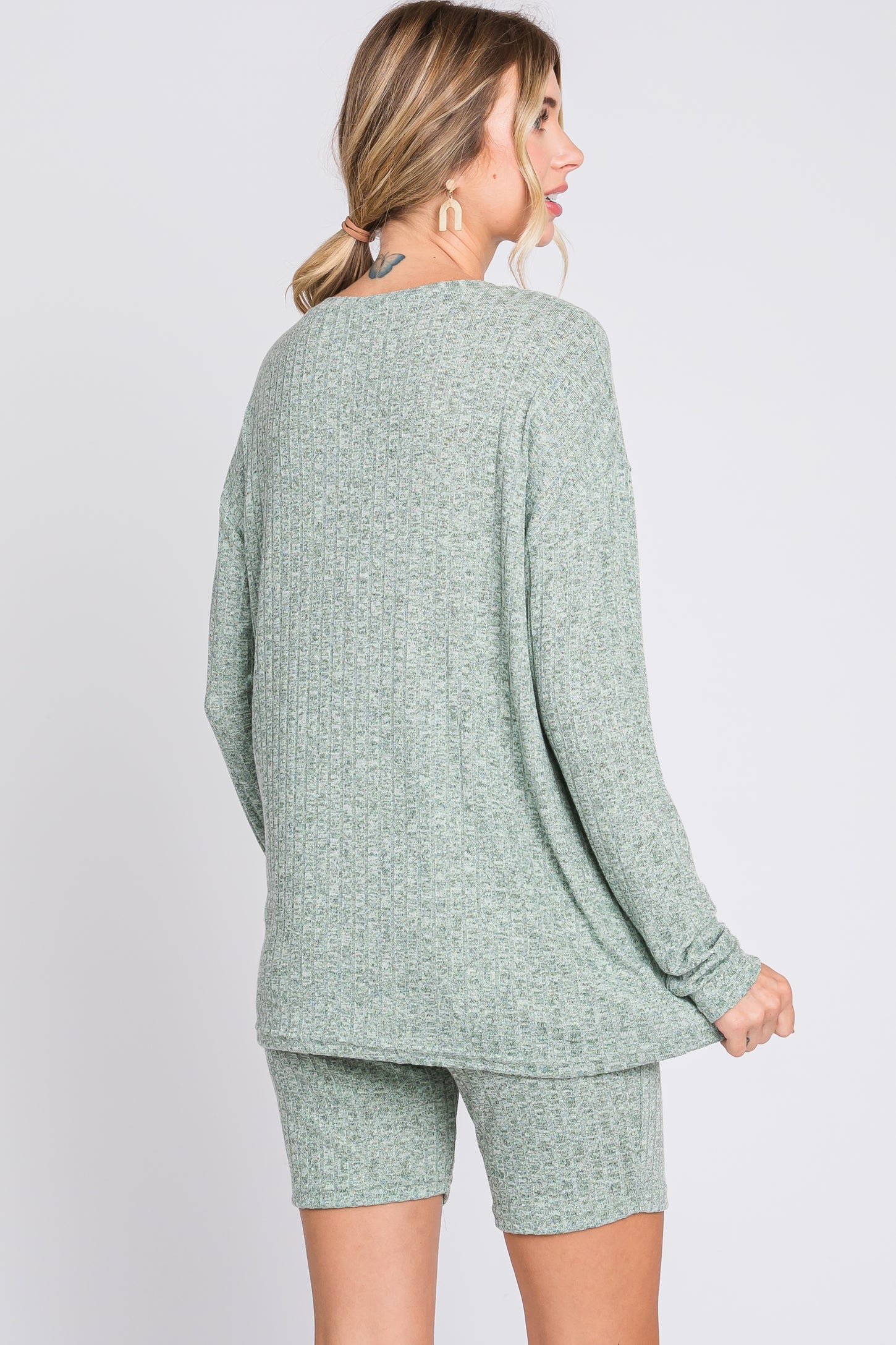 woman wearing a green ribbed knit oversized sweater and matching shorts, viewed from the back