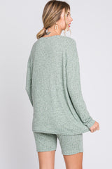woman wearing a green ribbed knit oversized sweater and matching shorts, viewed from the back