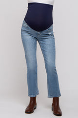 woman wearing a pair of light blue maternity jeans with a dark blue belly panel and distressed details, paired with brown ankle boots