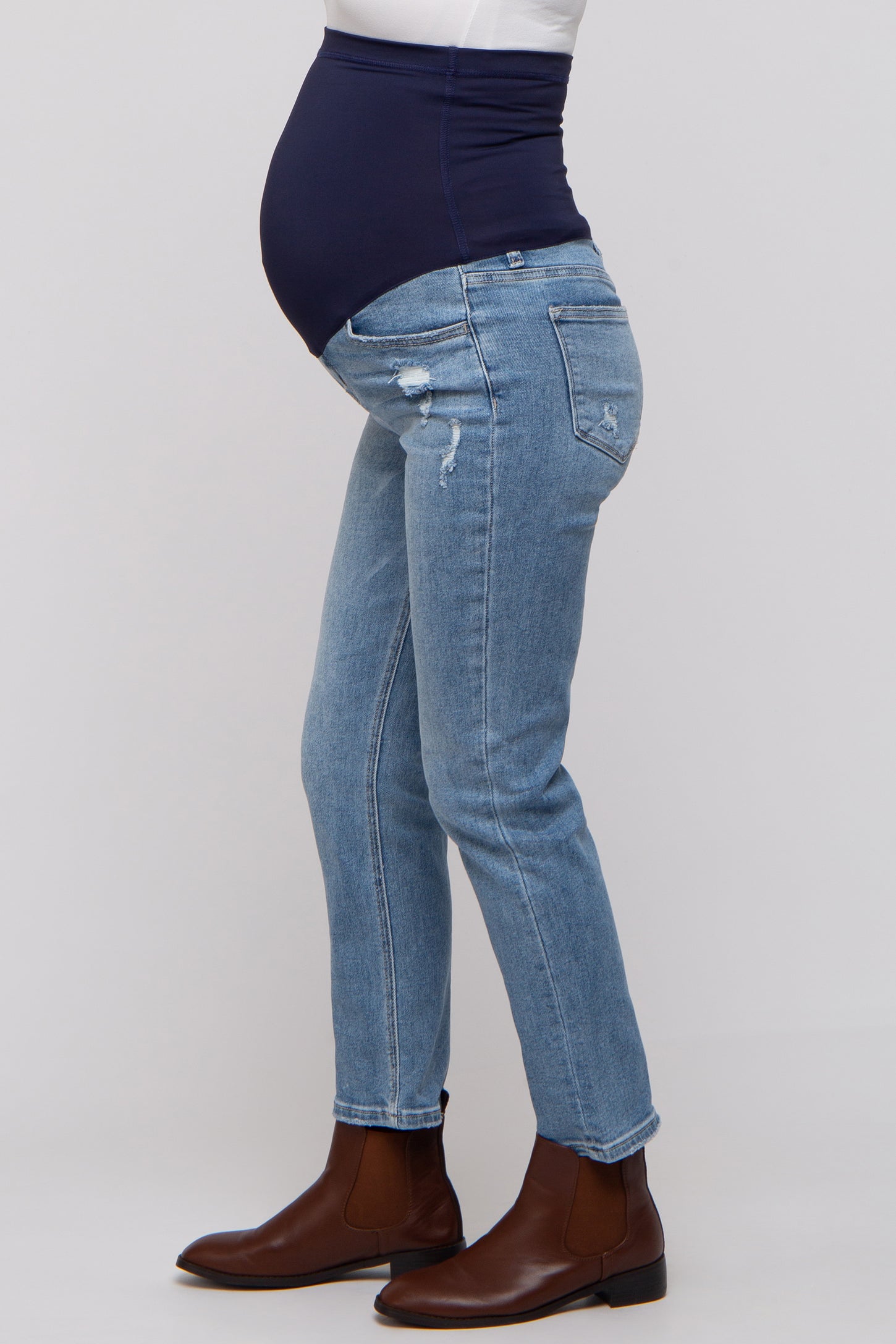 woman wearing a pair of distressed light blue maternity jeans with a navy waistband and a visible baby bump