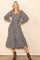 woman wearing a black and white checkered long sleeve midi dress with puff sleeves and a tiered skirt, posing confidently