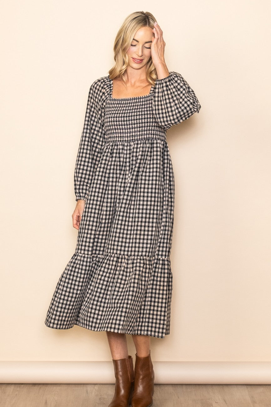 woman wearing a black and white checkered long sleeve midi dress with a square neckline and tiered skirt