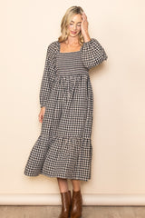 woman wearing a black and white checkered long sleeve midi dress with a square neckline and tiered skirt