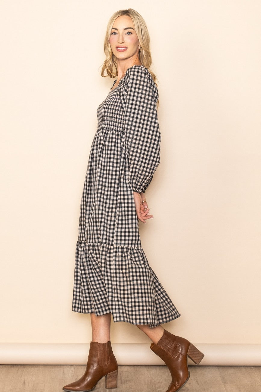 woman wearing a black and white checked long sleeve midi dress with tiered skirt and brown ankle boots