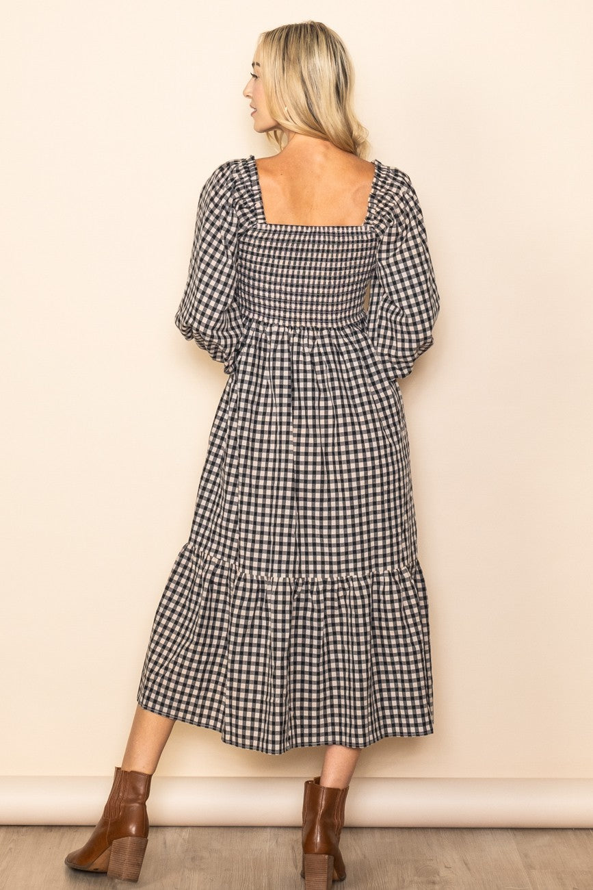 woman wearing a black and white gingham midi dress with puff sleeves and a tiered skirt