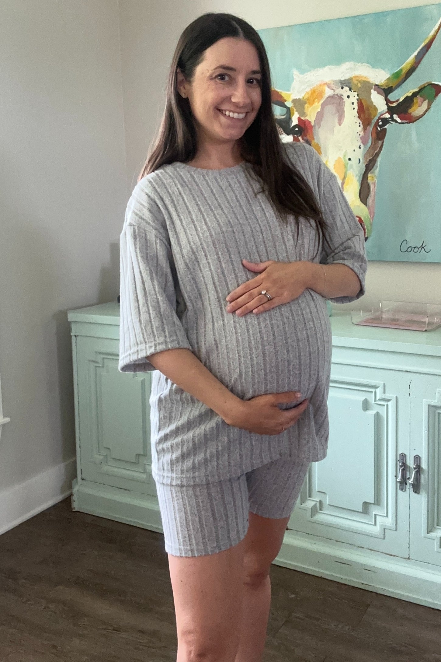 woman wearing a gray striped maternity shorts set and holding her baby bump