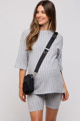 woman wearing a gray ribbed maternity top and matching shorts, smiling and carrying a black crossbody bag
