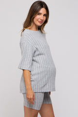 woman wearing a grey ribbed maternity set with short sleeves and shorts, showcasing a visible baby bump