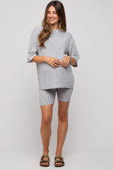 woman wearing a gray ribbed maternity top and matching shorts, smiling with a visible baby bump