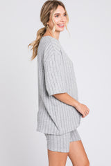 woman wearing a gray ribbed oversized t-shirt and matching shorts, smiling and posed sideways