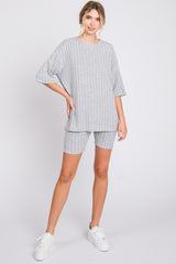 woman wearing a grey ribbed oversized sweater and matching biker shorts with white sneakers