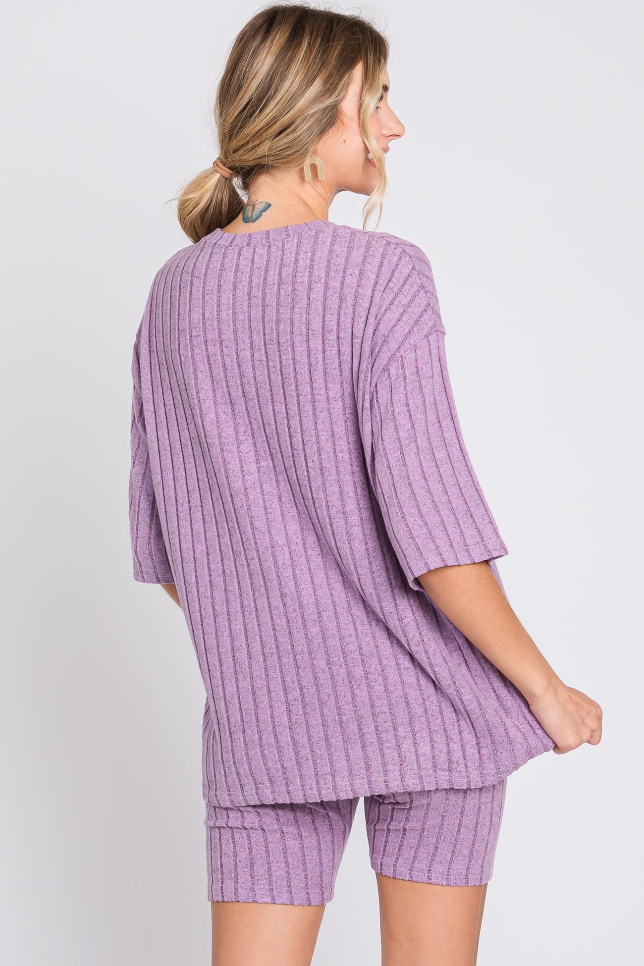 woman wearing a lavender ribbed oversized t-shirt and matching shorts, view from the back