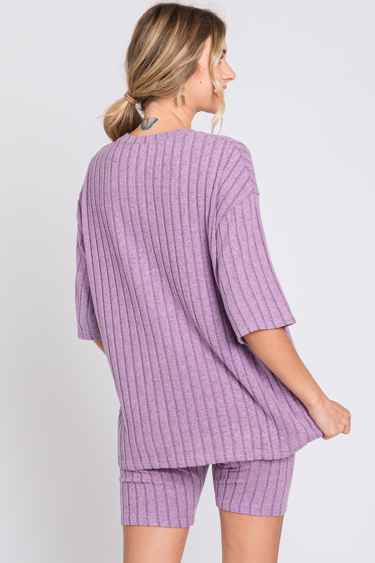 woman wearing a lavender ribbed oversized t-shirt and matching shorts, view from the back