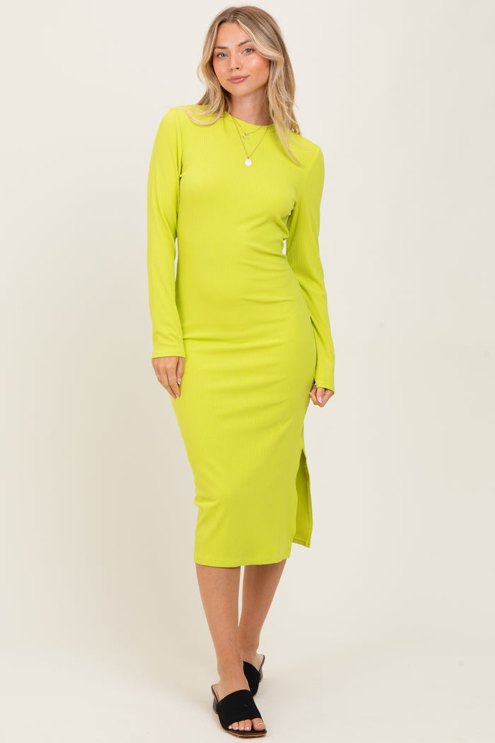 woman wearing a bright yellow long sleeve ribbed midi dress with a side slit and black mules