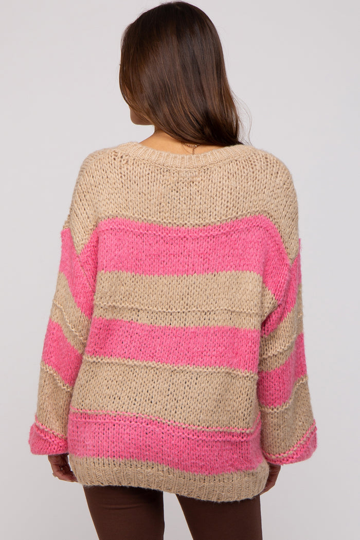 woman wearing a beige and pink striped oversized maternity sweater, showing the back view