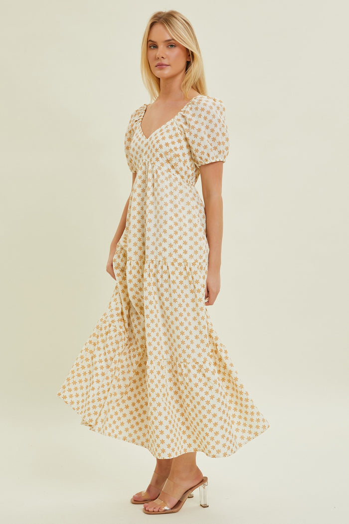woman wearing a white and yellow floral print maxi dress with puff sleeves and a v-neckline