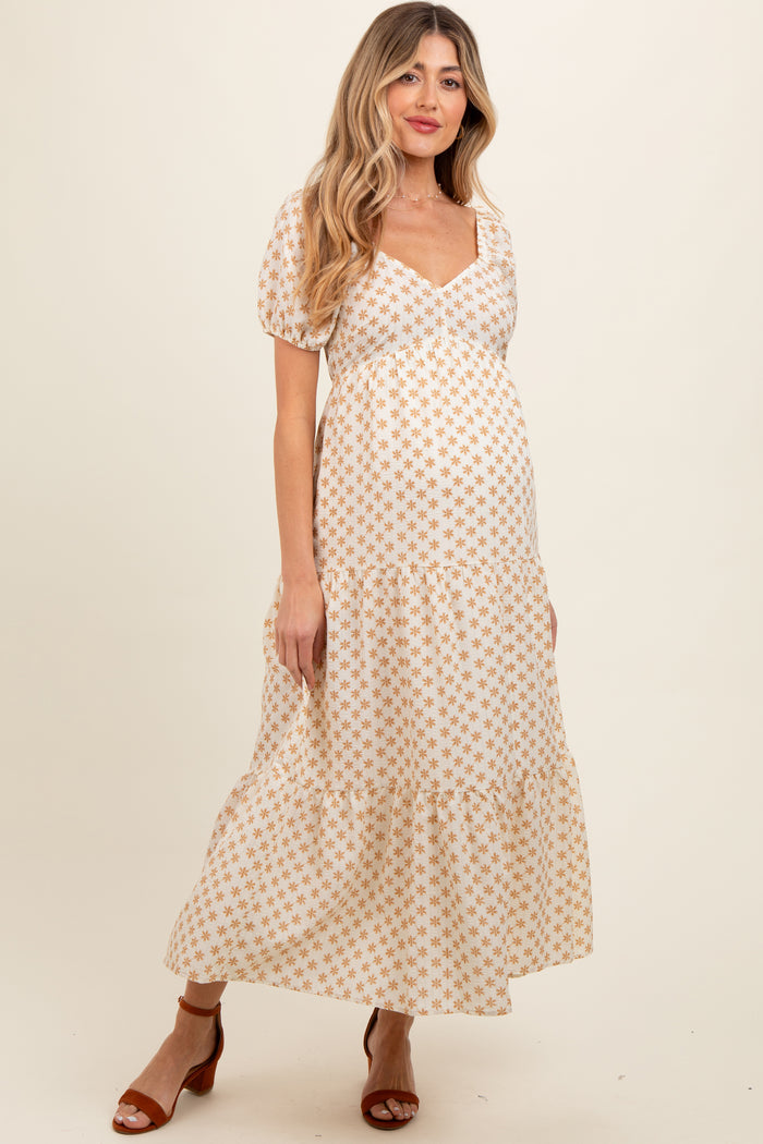 woman wearing a white floral print maternity maxi dress with puff sleeves and a tiered skirt, showing her baby bump