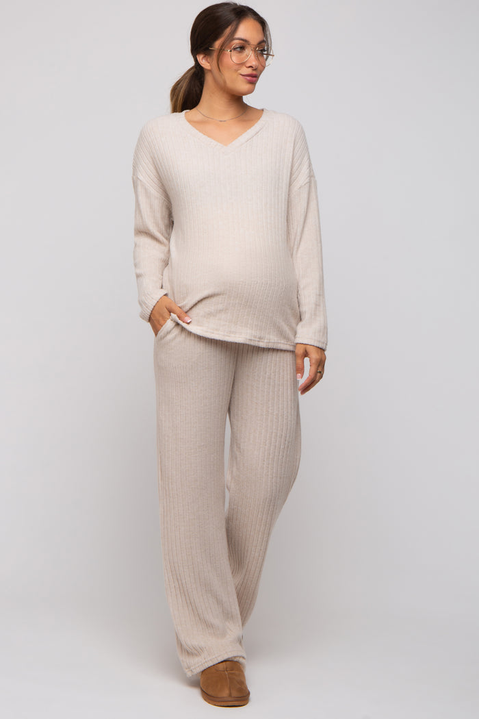 woman wearing a beige ribbed maternity top and matching pants, showcasing her baby bump, styled with glasses and a relaxed fit