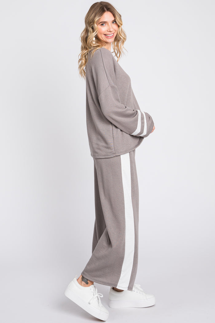 woman wearing a gray lounge set with white stripes on the pants and long sleeves, paired with white sneakers