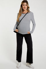 woman wearing a black and white striped maternity top with a baby bump and black wide-leg pants, carrying a crossbody bag