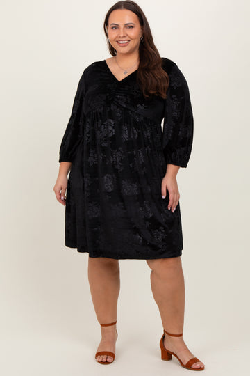 woman wearing a black floral plus size dress with a pleated v-neckline and three-quarter sleeves