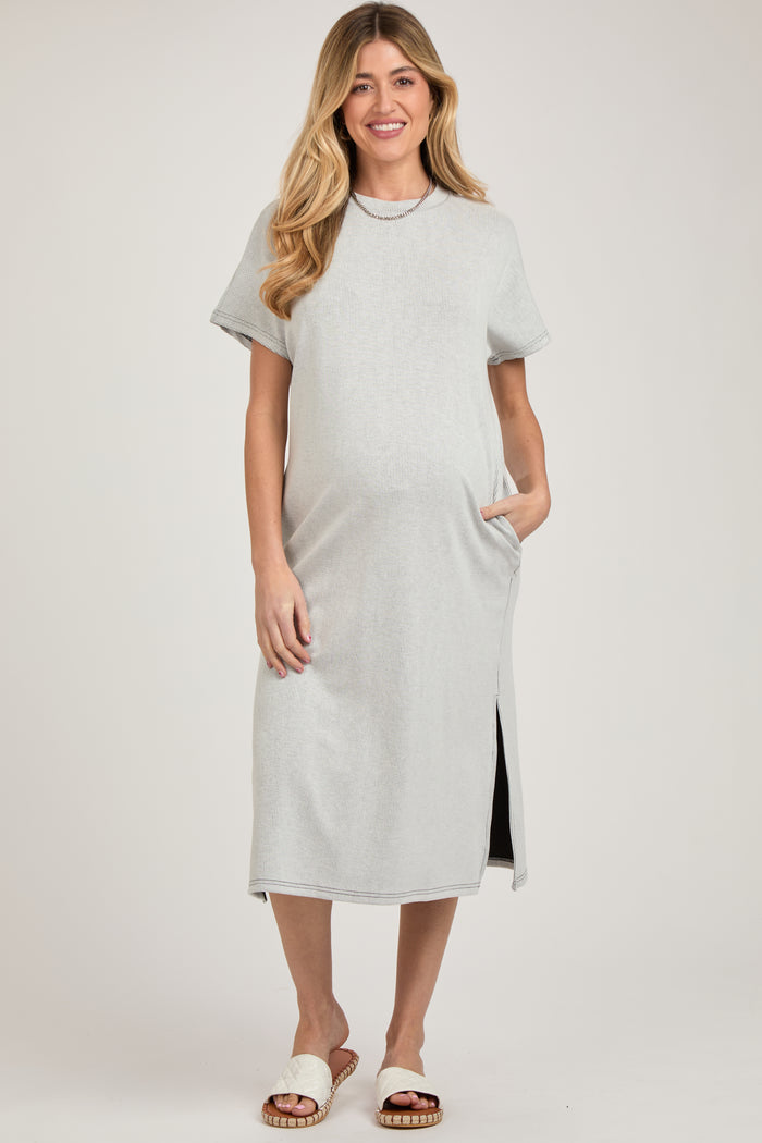 woman wearing a light gray ribbed maternity dress with side pockets and short sleeves, showcasing her baby bump