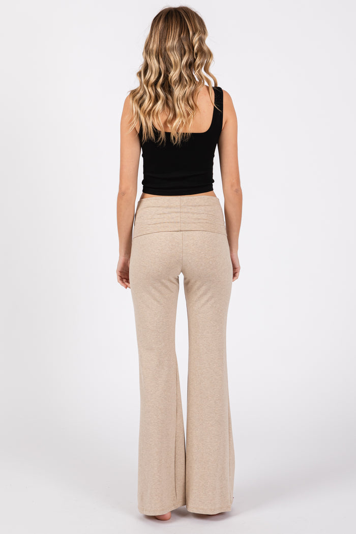 woman wearing a black fitted tank top and light beige flared pants, seen from the back