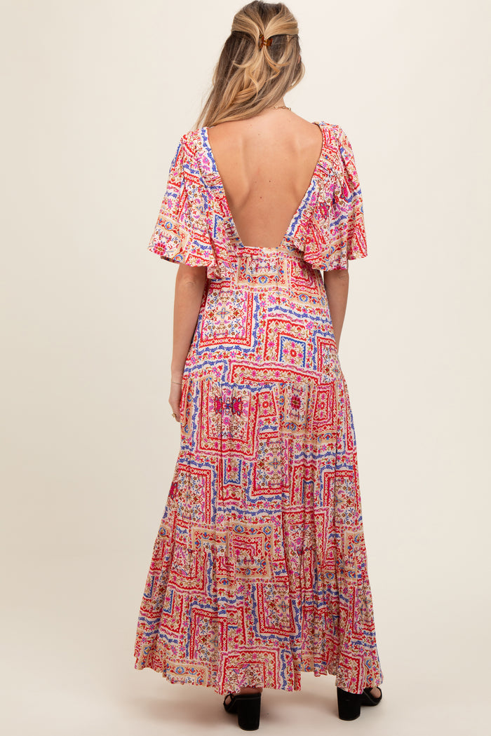 woman wearing a colorful patterned maternity maxi dress with flutter sleeves and an open back