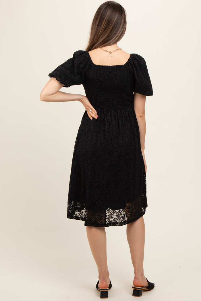 woman wearing a black maternity dress with puff sleeves and a fitted bodice, showing a relaxed fit at the back