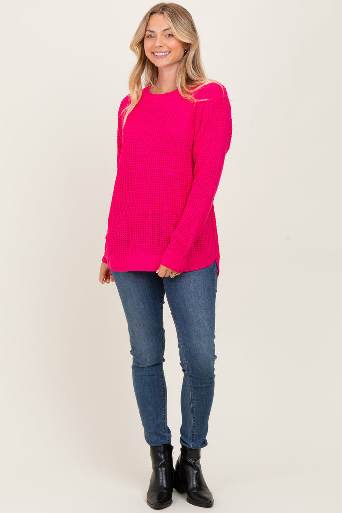 woman wearing a bright pink knit sweater with long sleeves paired with blue jeans and black ankle boots