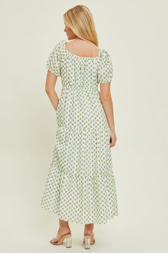 woman wearing a green floral print maxi dress with puff sleeves and a tiered skirt, shown from the back