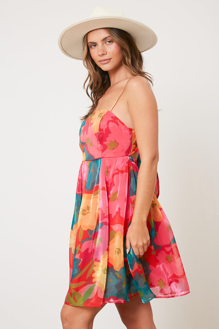 woman wearing a colorful floral print sundress with a flared skirt and a wide-brimmed hat