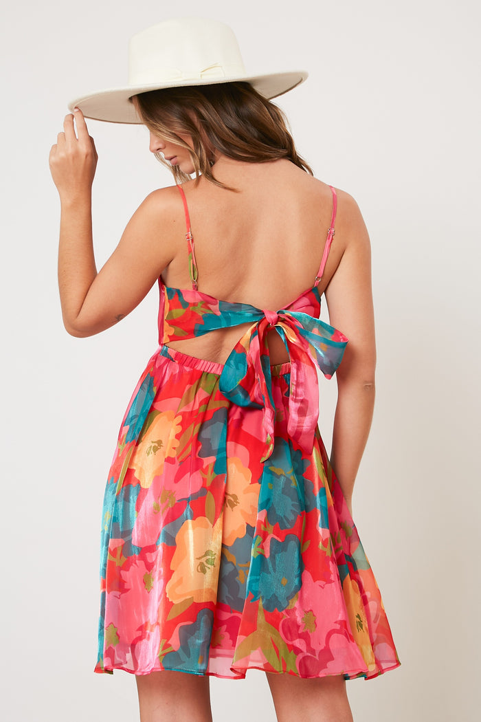woman wearing a colorful floral sundress with a tied back detail and a wide-brimmed hat