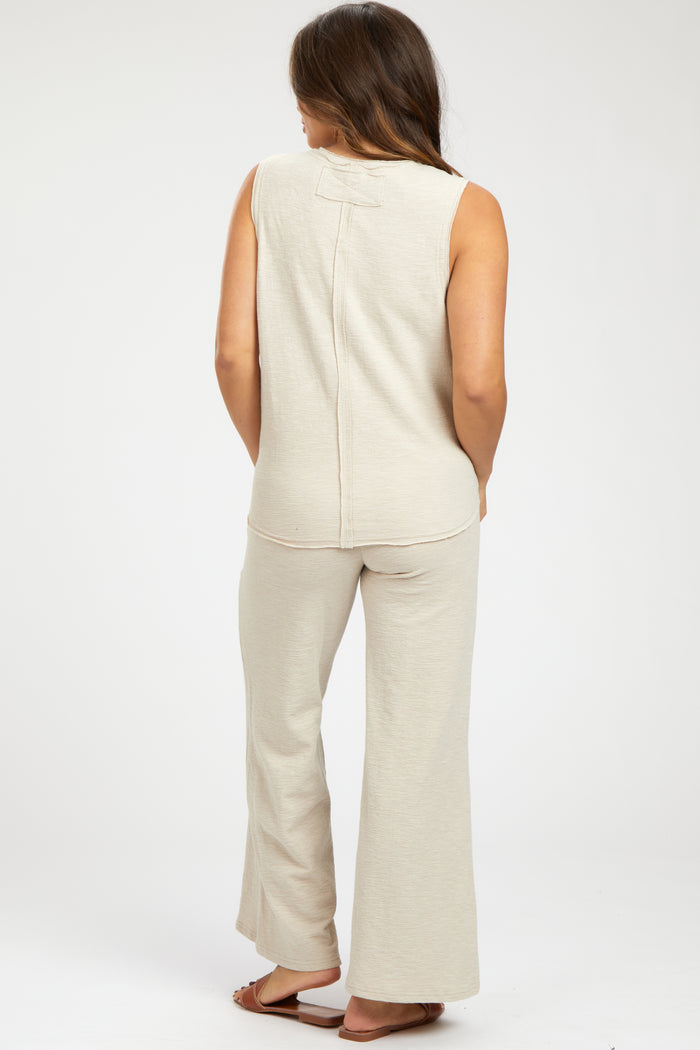 woman wearing a beige sleeveless maternity top and matching wide-leg pants, showing her back