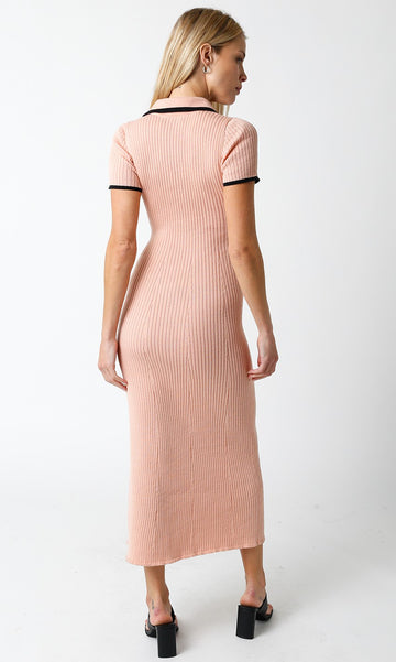 woman wearing a fitted light pink ribbed maxi dress with short black-trimmed sleeves, seen from the back