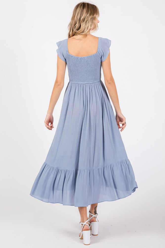 woman wearing a light blue flutter sleeve maxi dress with a smocked bodice and tiered skirt