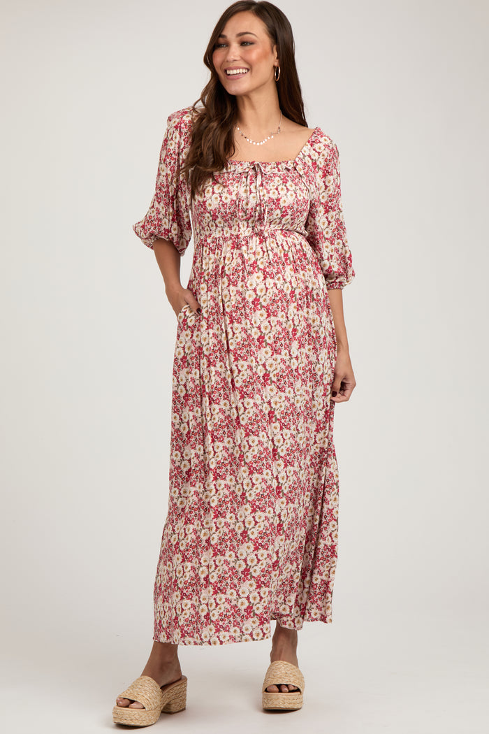 woman wearing a floral print maternity maxi dress with a square neckline and puff sleeves, showcasing her baby bump