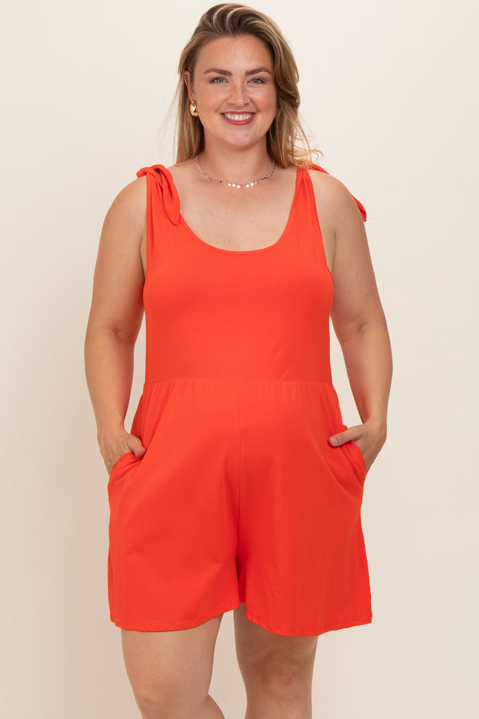 woman wearing a bright orange maternity plus romper with bow tie straps and pockets