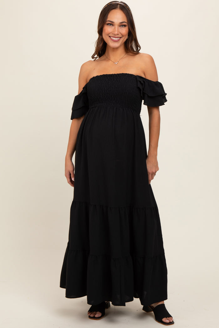 woman wearing a black off-the-shoulder maternity maxi dress with ruffle details and a visible baby bump