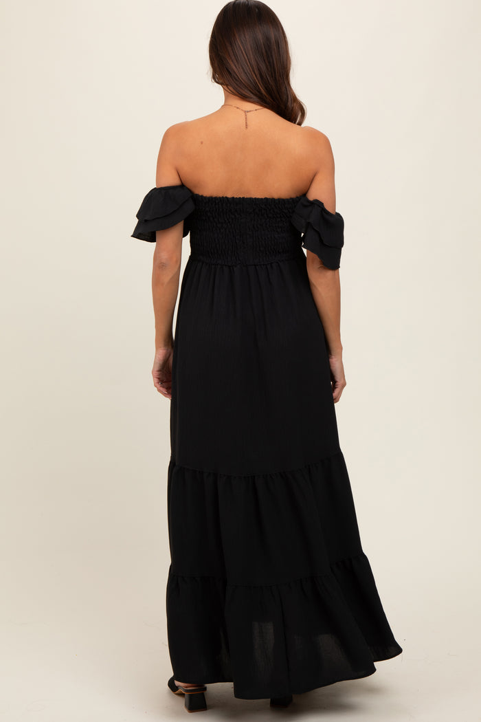 woman wearing a black off-the-shoulder tiered maternity dress, showing back view and flowing fabric