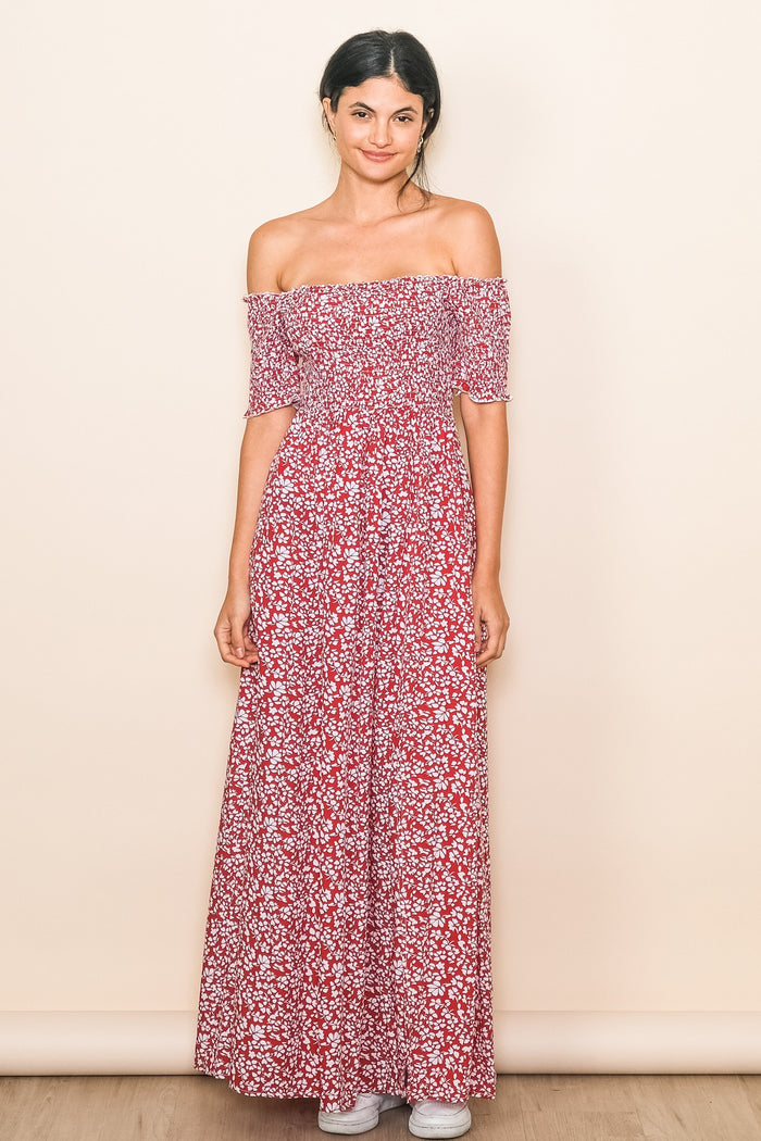 woman wearing a red off-the-shoulder maxi dress with a floral print and a smocked bodice