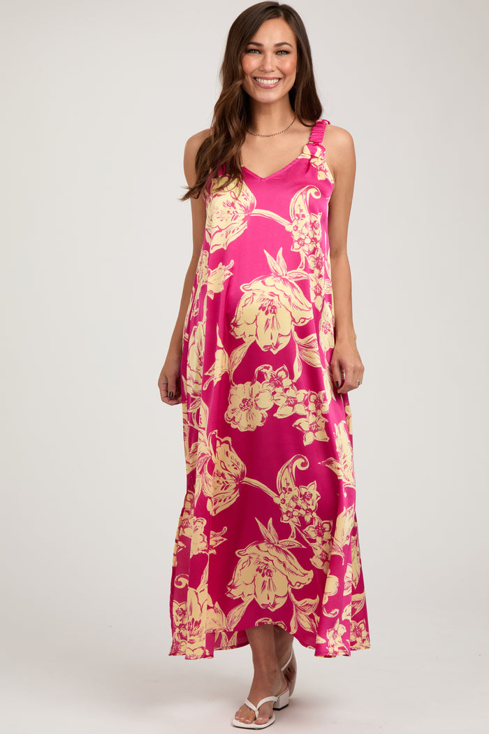 woman wearing a pink floral maternity maxi dress with adjustable straps and a flowing silhouette, showing her baby bump