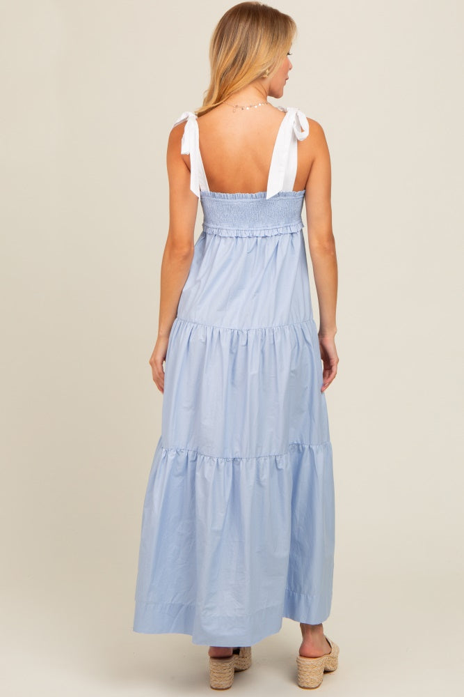 woman wearing a light blue maxi dress with smocked bodice and white tie straps, showing the back view