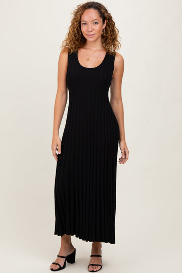 woman wearing a black ribbed maxi dress with a fitted bodice and flared skirt, posing in a neutral background