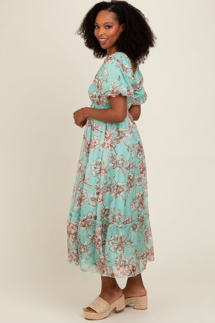 woman wearing a mint green floral maxi dress with puff sleeves and a tiered hem, standing sideways