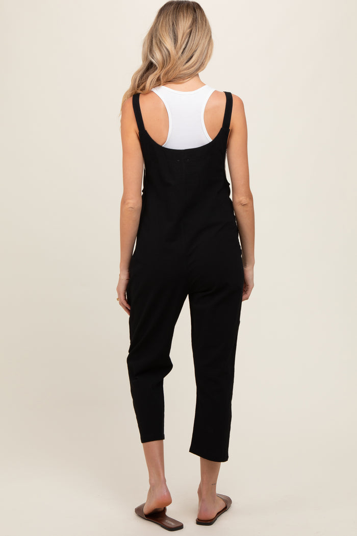 woman wearing a black maternity jumpsuit with adjustable straps, viewed from the back