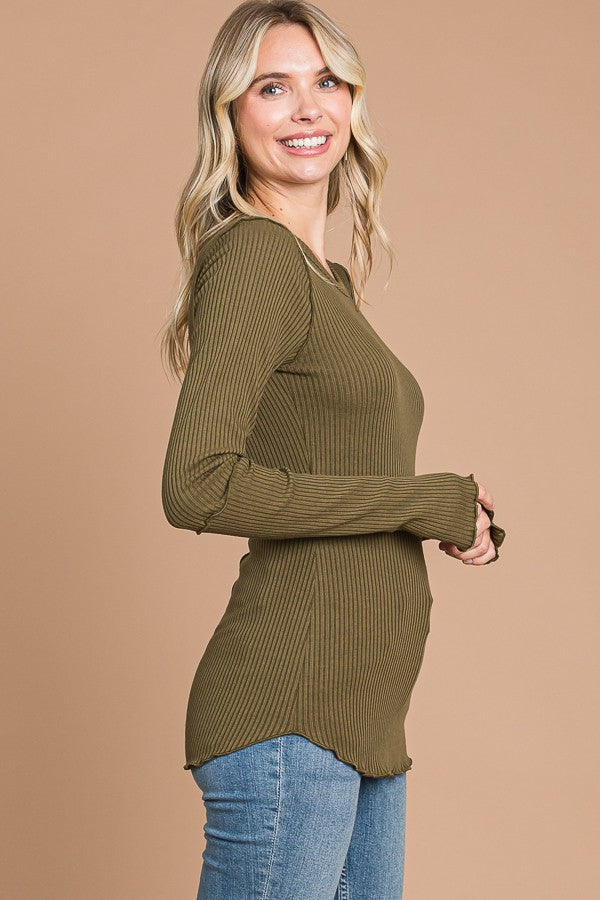 woman wearing a long sleeve olive green ribbed top with a curved hem and side slits, styled with blue jeans