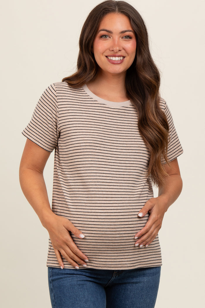 woman wearing a light brown and cream striped maternity top and holding her baby bump